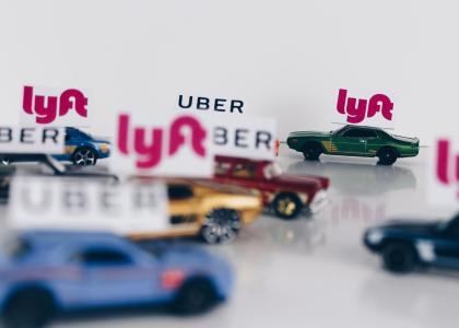 Toy cars, in and out of focus, with "Uber" and "Lyft" tags above them