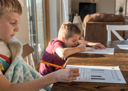 Two little boys doing school work from home during home schooling period