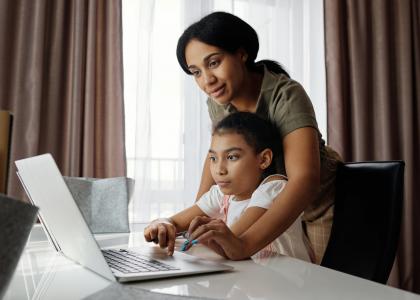 mother helping daughter use her laptop