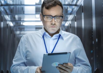 SES blog banner man standing near servers on tablet