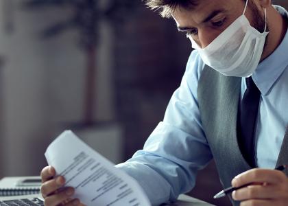 Man at desk with paperwork wearing mask