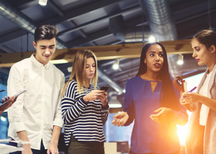 Group of people looking at phones and talking 