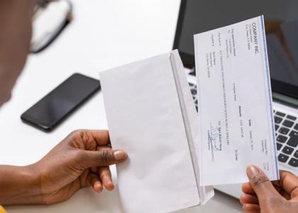 A woman is looking at a pay slip having just removed it from its envelope