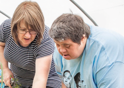 Camphill village trust carer pictured helping a member at an allotment