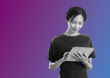 A lady stood looking at a tablet she is holding.