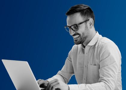 a man sat with a laptop smiling.