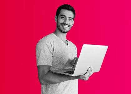 a man smiling to the side holding a laptop.