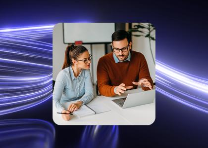 Two payroll employees at a small business talking over a laptop.