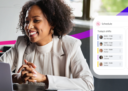 woman smiling at laptop screen whilst looking at a workforce management scheduling software