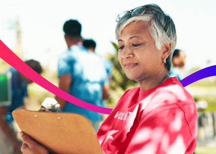 Volunteer looking at clipboard with other volunteers in the background