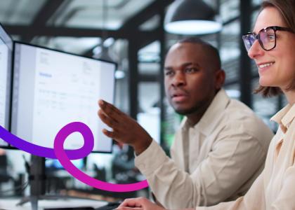 A man and woman working at a desk looking at computer screens.