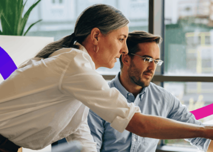 man and woman in an office looking at a computer screen