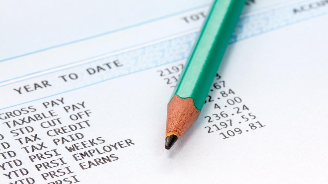 Pencil on a paper payslip showing deductions