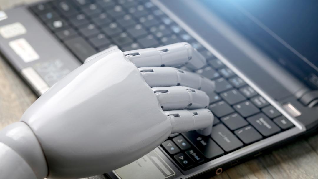 Robot hand typing on a laptop keyboard