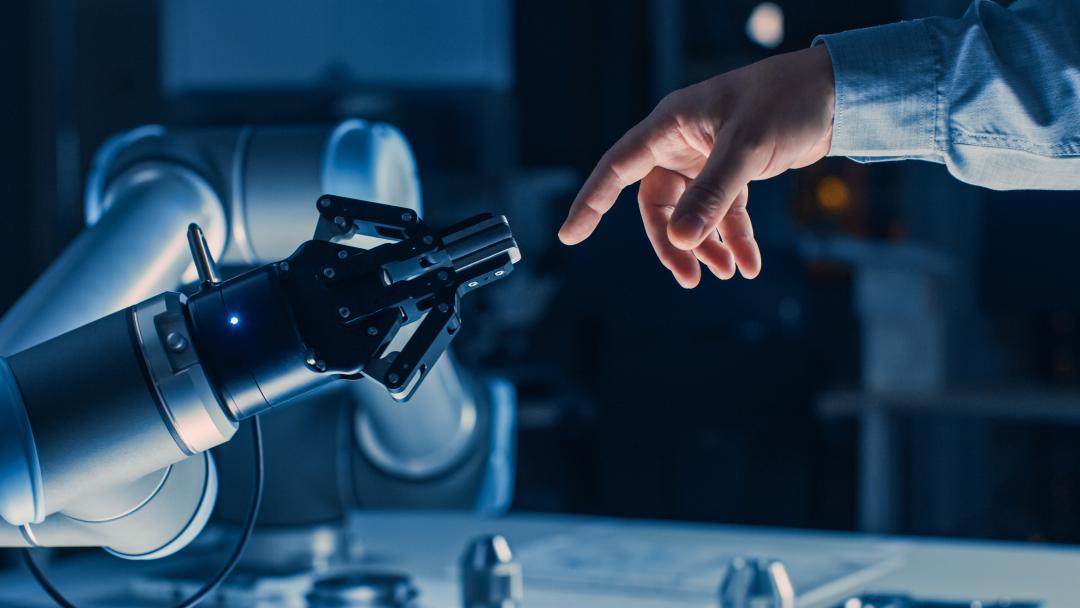 Human hand reaching out to a robot arm, representing the relationship between humans and AI