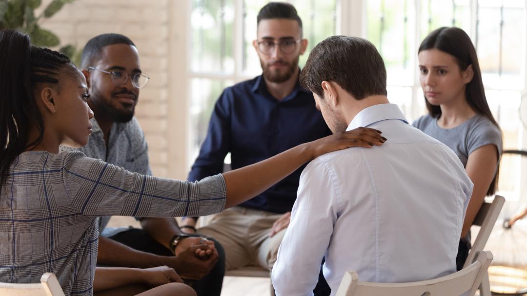 Group of office workers consoling a colleague to represent Mental Health Awareness Week