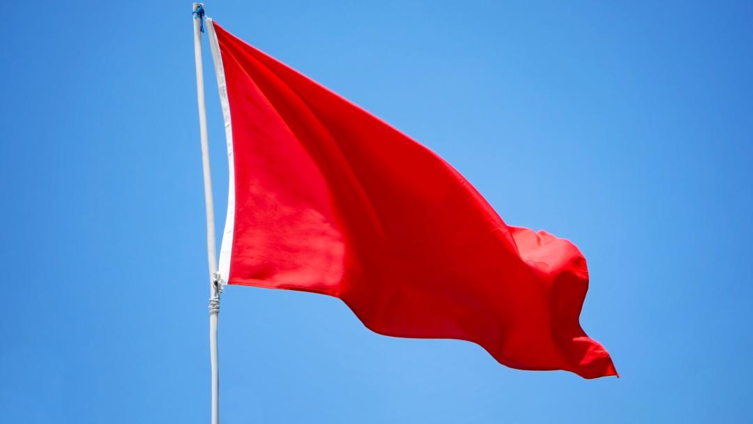 Red flag waving in the wind, representing red flags or 'icks' in the office