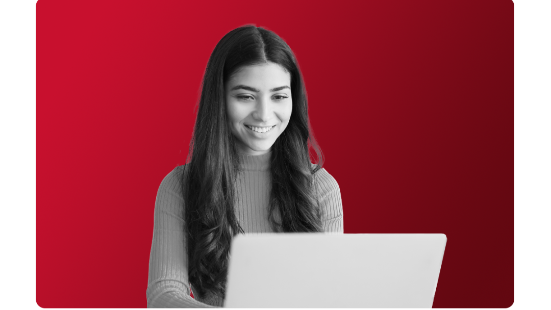 Woman smiling at her laptop with streamlined Manufacturing ERP processes meaning she's able to reduce costs