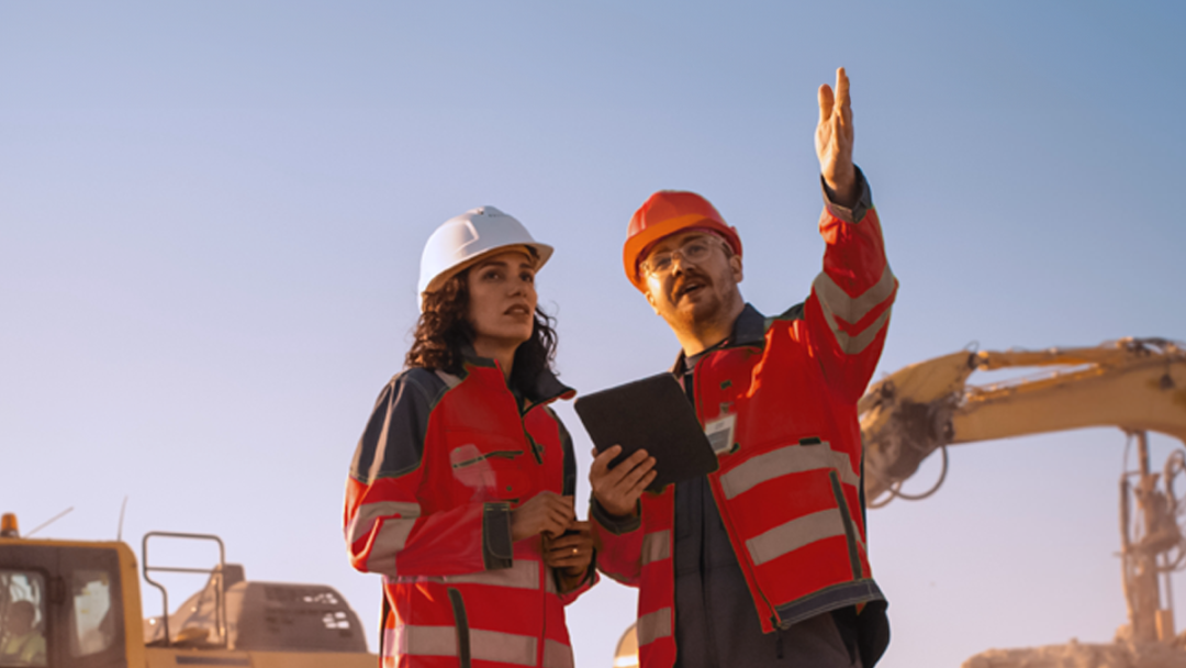 Two people on a construction site, using People First HR software remotley.