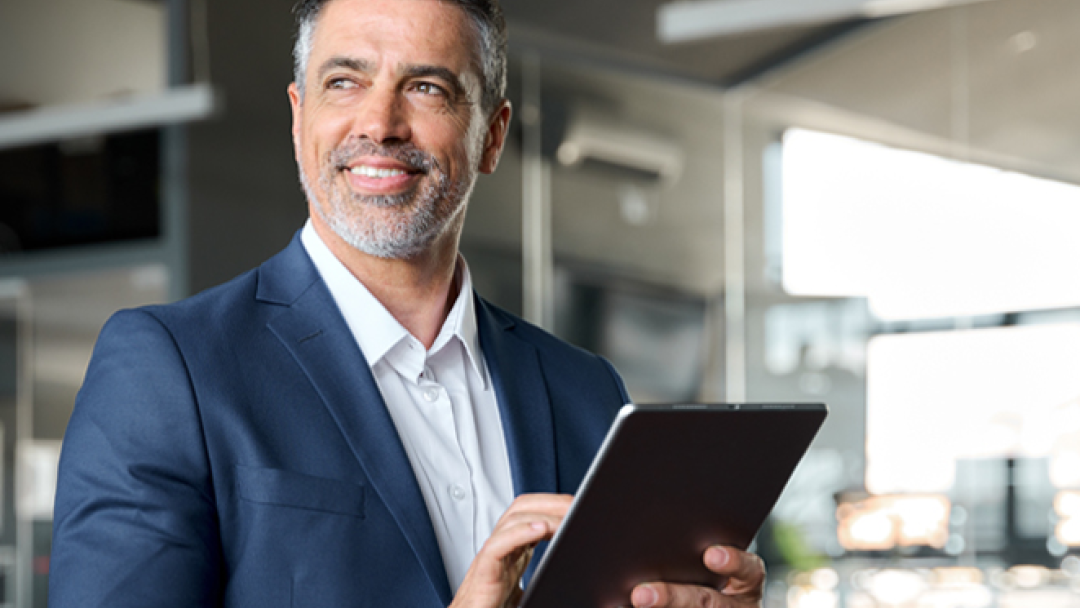 a man stood in an office, using a tablet accessing MHR's finance software integrations.