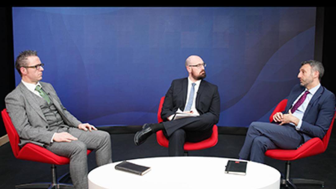 Three people sat on seats having a conversation.