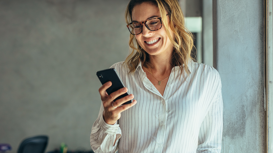 Woman smiling whilst holding phone in her hand