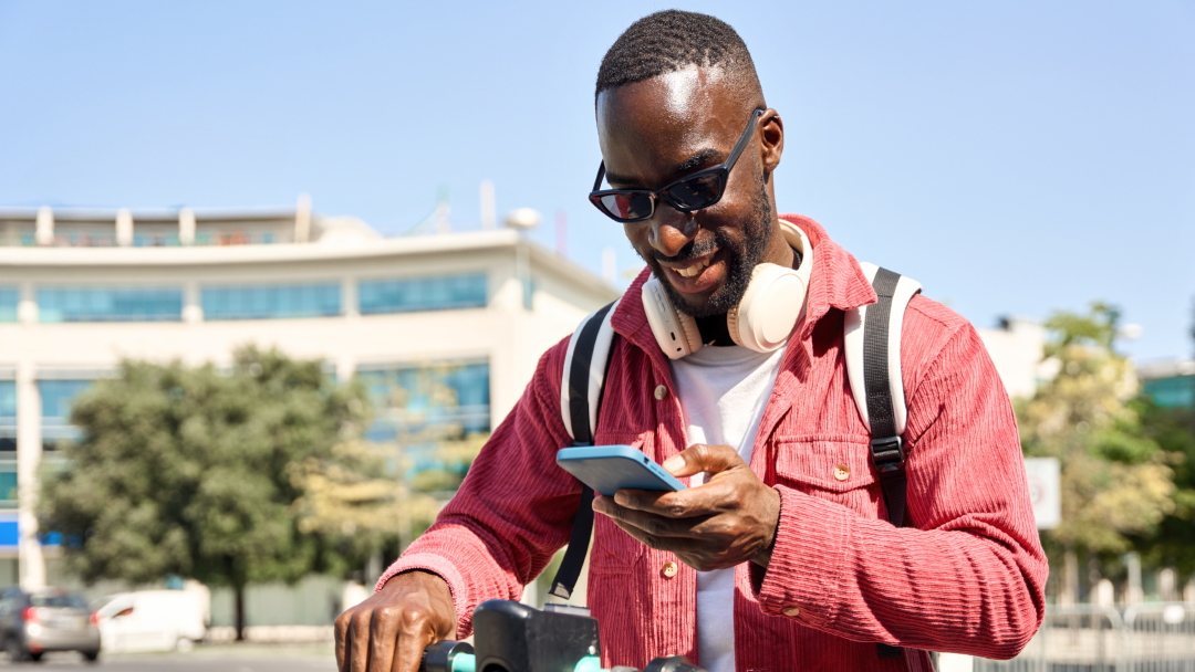 Young male in outdoor environment looking at People First platform on mobile device