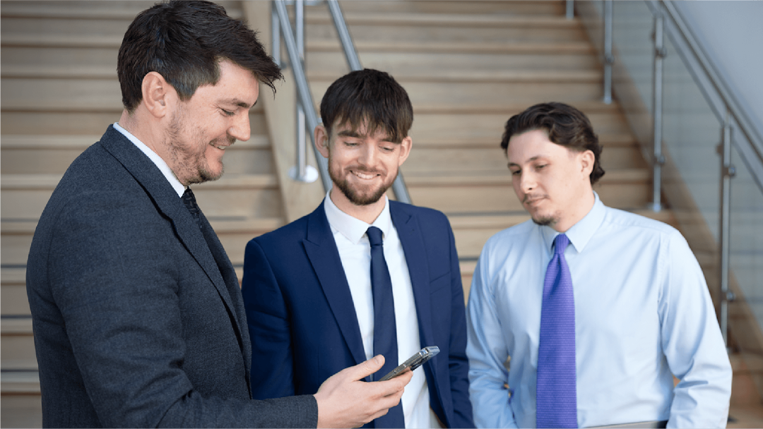 Three colleagues reviewing information together on a mobile phone