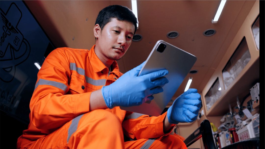 Emergency medical worker using a tablet while reviewing information in an ambulance