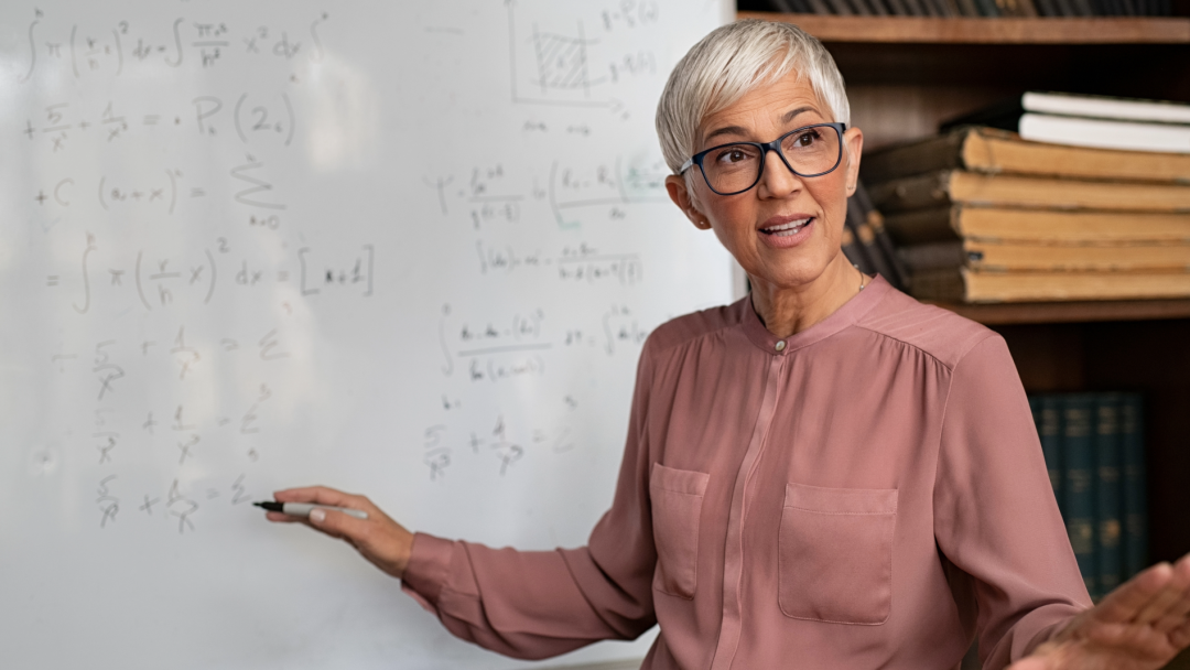 Teacher explaining mathematical equations on a whiteboard during a lesson in a university classroom