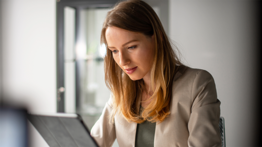 Employee reviewing information on a tablet while seated at a desk in an office