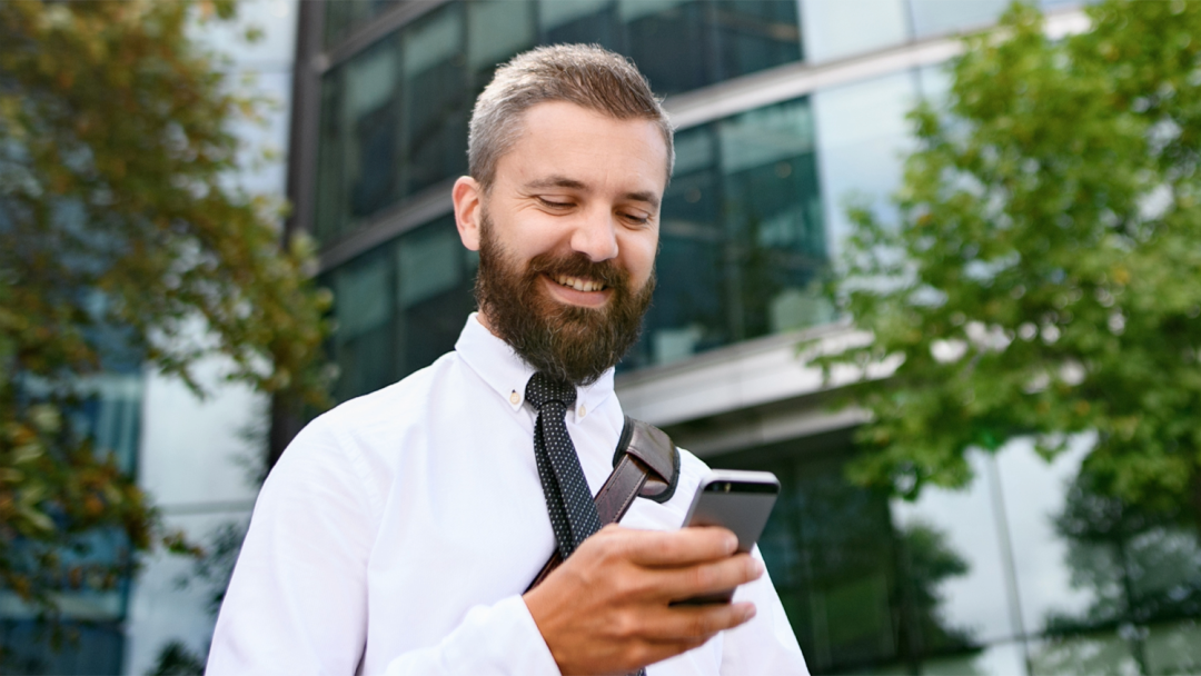 Employee using a smartphone outside a modern office building