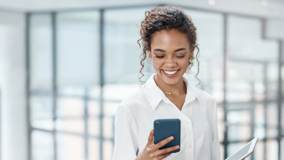Employee checking a smartphone while holding a tablet in a modern office