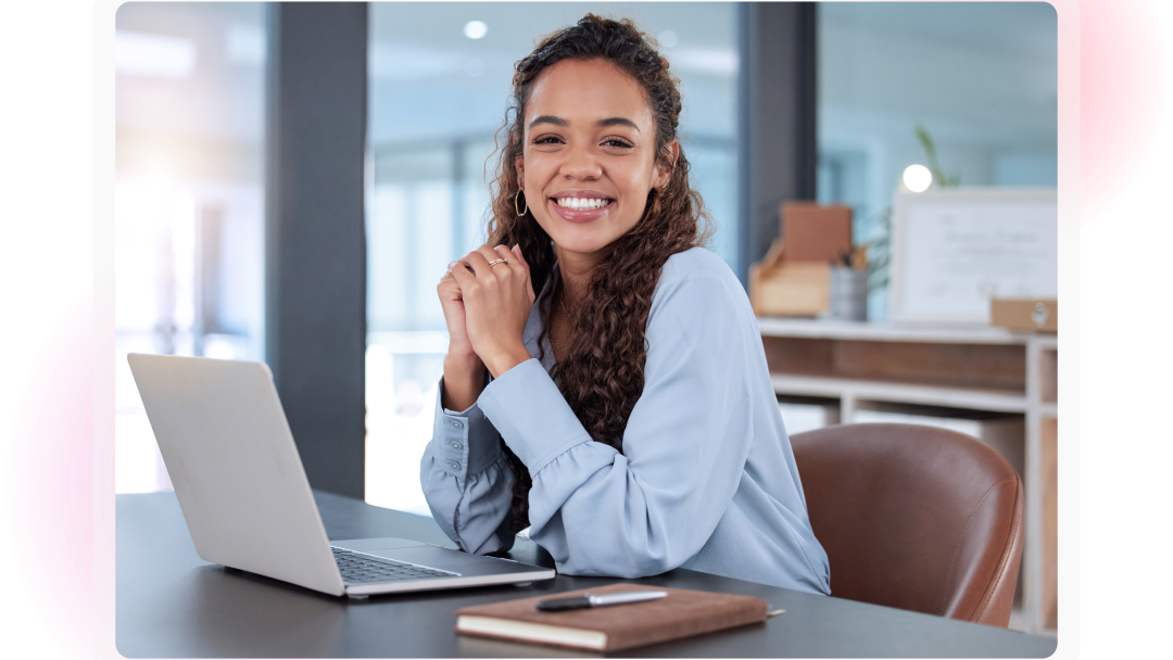 Smiling employee seated at a desk with a laptop in a modern office