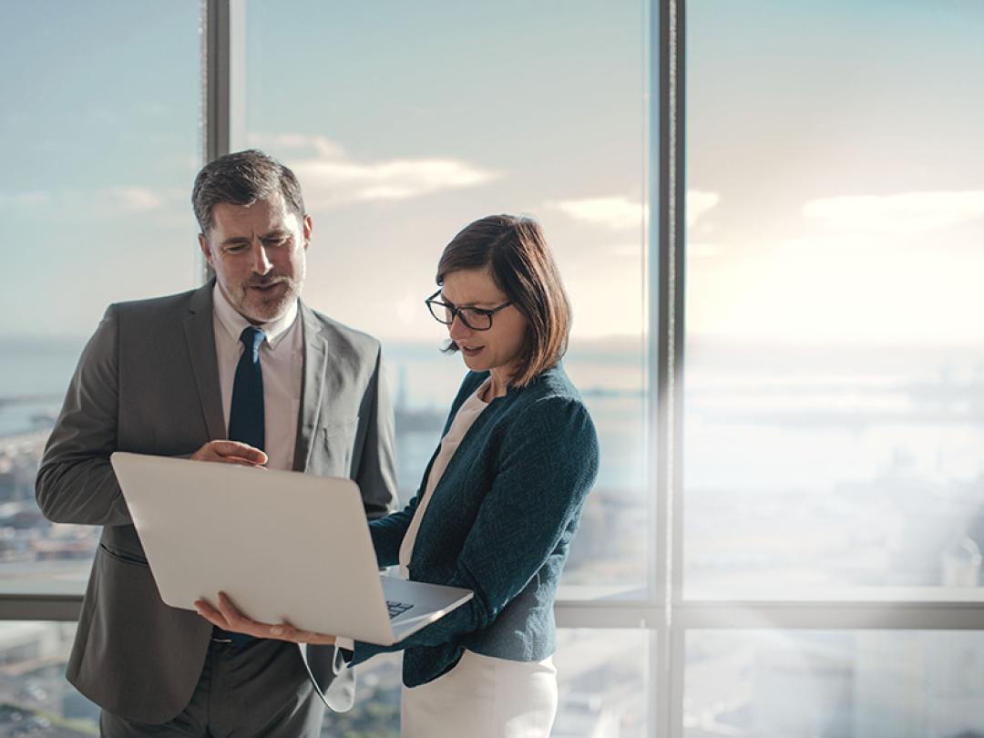 Two employees in suits looking at a laptop