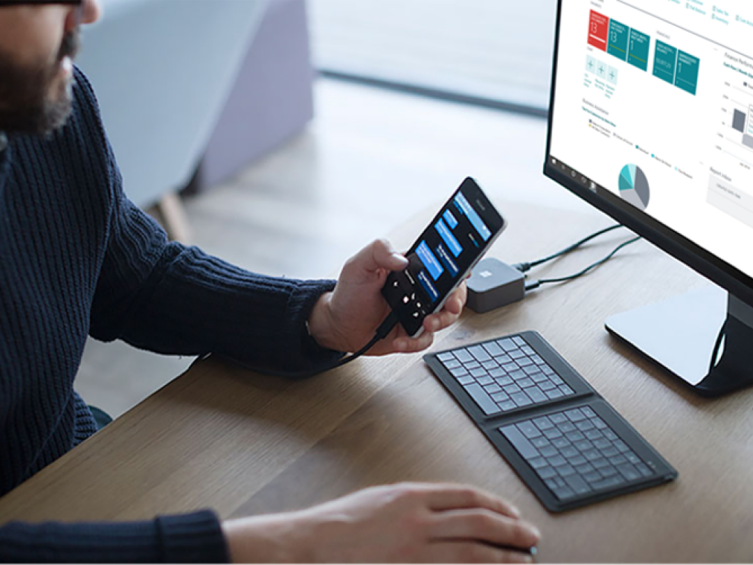 man on phone and computer showing microsoft dynamics on screen