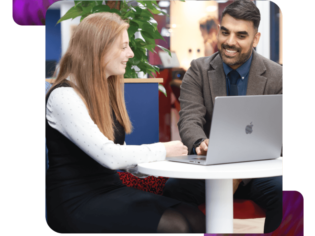 Two people having a discussion, looking at a laptop.
