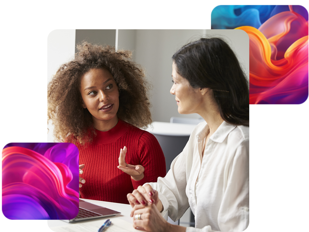Two women having a conversation, with a laptop in front of them.