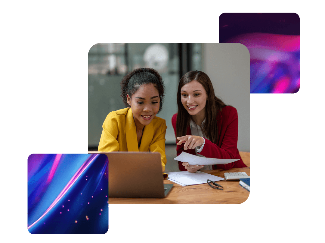 Two women looking at laptop screen, one pointing at something on screen and smiling 