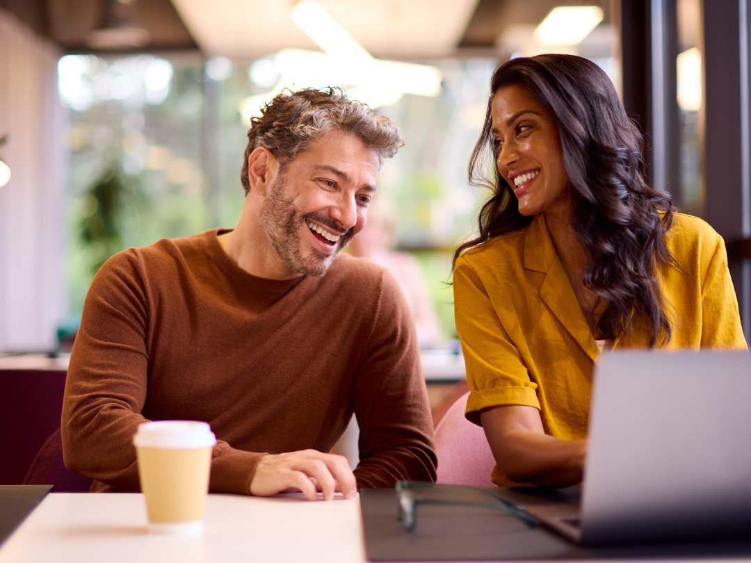 woman and man smiling looking at a laptop