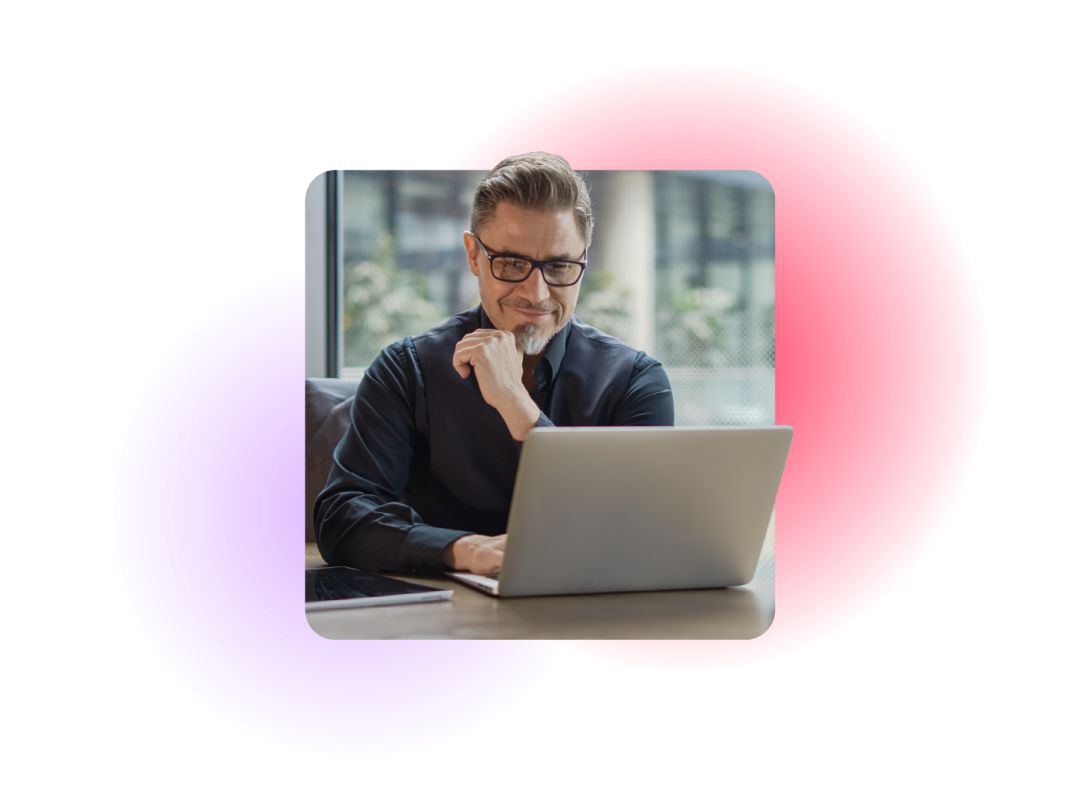 man smiling whilst looking at a laptop