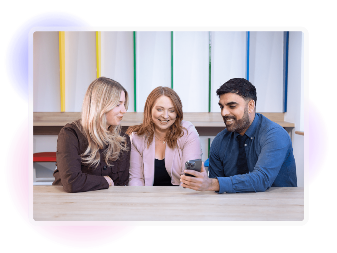 Three colleagues smiling and collaborating in the workplace