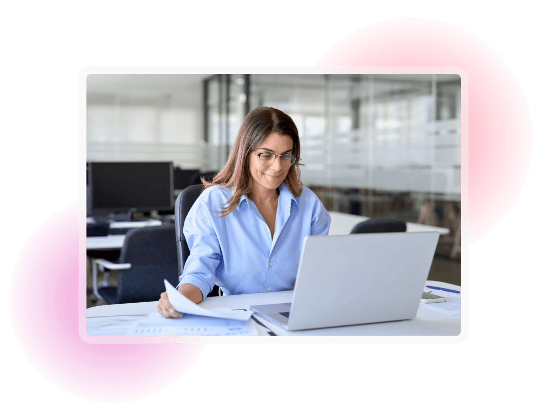 Professional reviewing documents and working on a laptop in a modern office