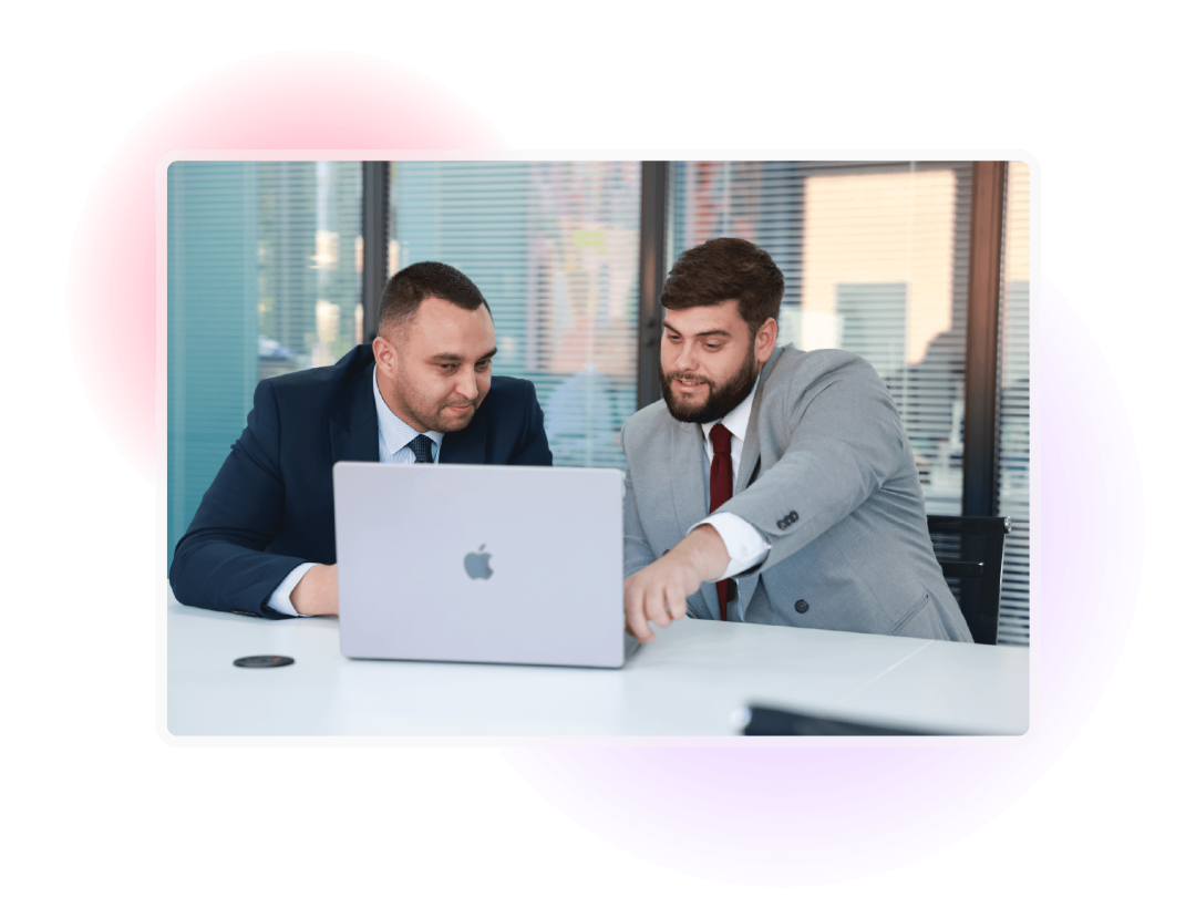 Two colleagues collaborating on a laptop in a modern office workspace