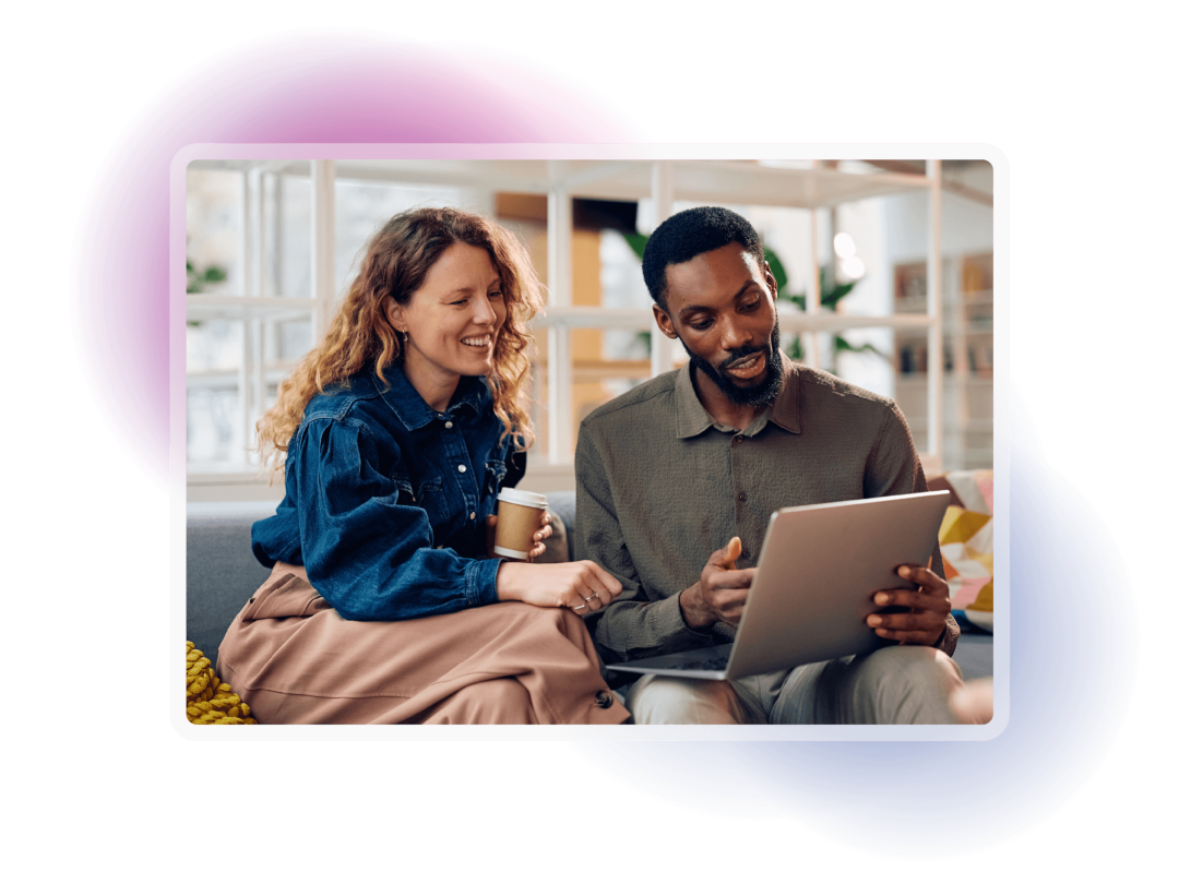 Two colleagues reviewing information together on a laptop while sharing a coffee, representing collaboration and teamwork