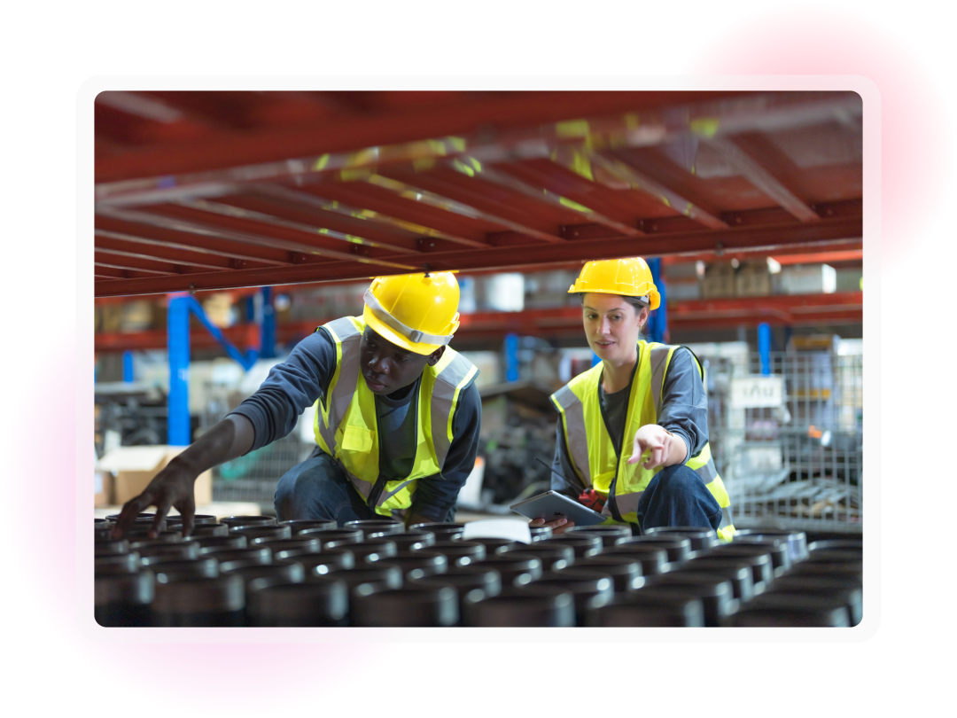 Two workers in reflective workwear and hardhats examining stock