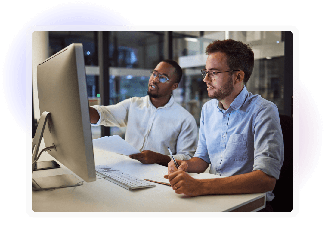 Two colleagues collaborating while reviewing information on a desktop computer