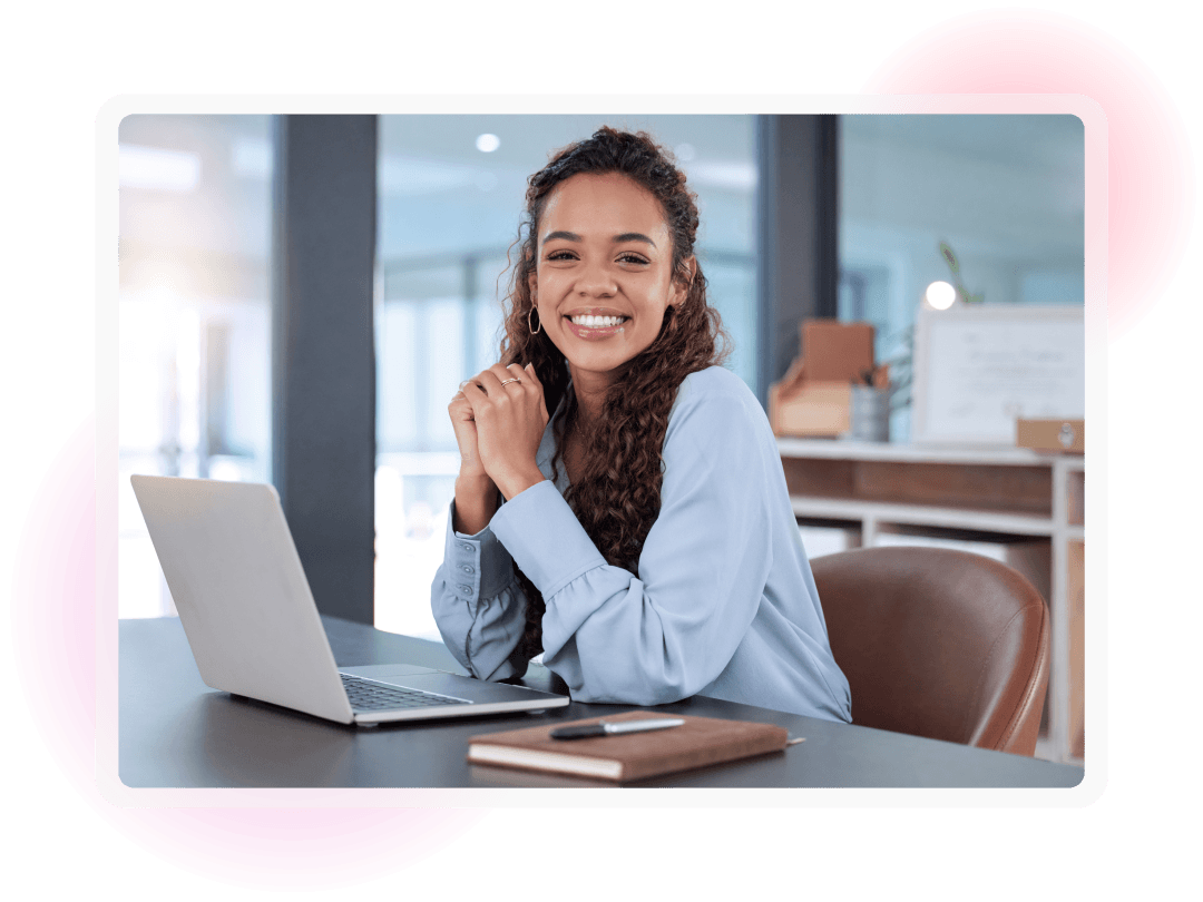 Smiling employee seated at a desk with a laptop in a modern office