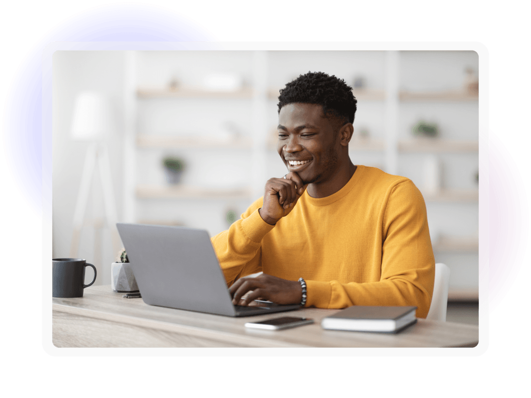 A man in a yellow jumper typing on a laptop