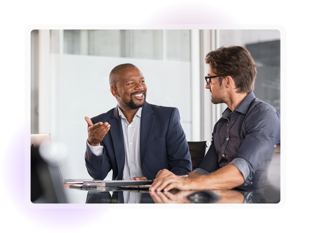Two men talking sat facing each other at a desk
